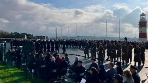 BBC Military personnel and veterans taking part in the Remembrance service on Plymouth Hoe. The red and white lighthouse is visible on the right hand side