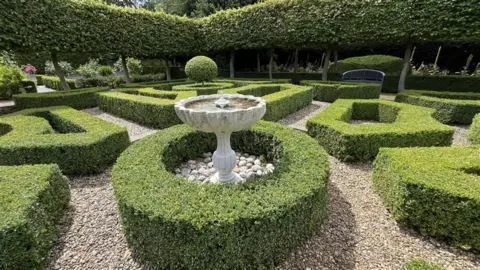 Shaun Whitmore/BBC Short hedges curving round each other with a water feature in the middle.