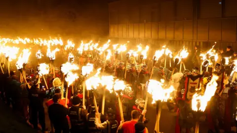 Reuters Hundreds of men and women carry torches ablaze in Lerwick