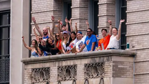 Getty Images People in Knicks gear waving from a terrace on a city building