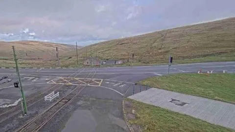 DOI The Mountain Road at the junction at the Bungalow showing the electric tram tracks and other infrastructure with the hills sloping into the Laxey Valley behind.