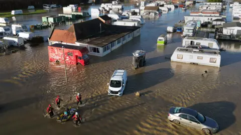 PA Media An aerial view of a flooded caravan park as a man is rescued.