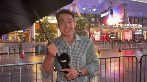 Floyd Cush battles with an umbrella in stormy conditions