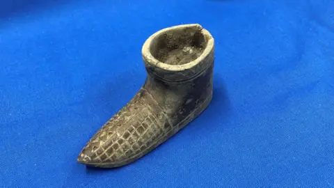 Alexandra Palace A tiny wooden shoe with an engraved pattern on the toes. The shoe is not hollow