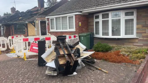Debris is left on the drive around barriers outside the front of the bungalow.