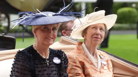 PA Media Sophie, the Duchess of Edinburgh and Anne, the Princess Royal, wearing blue and white hats respectively and wearing a blue dress and orange dress respectively.