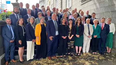 The States of Guernsey assembly for 2025-29 standing on the steps of the Royal Court. 