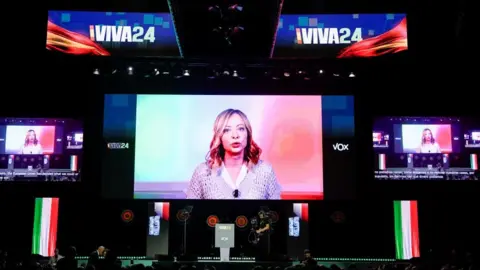 REUTERS/Ana Beltran Italian Prime Minister Giorgia Meloni speaks via video link during a rally organised by the Spanish far-right Vox party ahead of the European elections