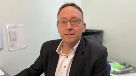 Man in white shirt and black suit jacket in an office