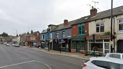 A street view of Abbeydale Road shows a row of shops and businesses. A traffic light is on green while several cars travel up the road.