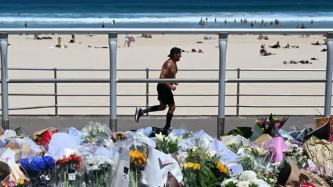 Getty Images A man jogging along Bondi Beach with a large collection of flowers in the foreground
