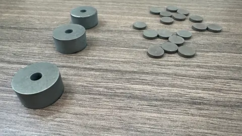 There are three objects on the left and more than a dozen smaller objects shaped like coins on the right.