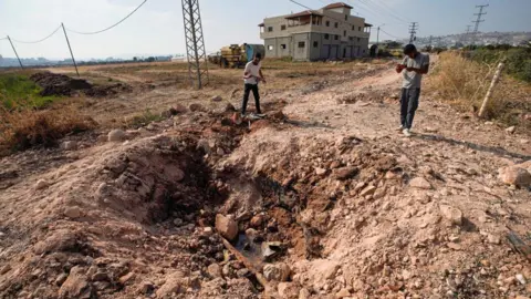 Palestinian men stand next to a small crater reportedly left by bomb explosion that targeted Israeli troops, near Jenin, in the occupied West Bank (27 June 2024)