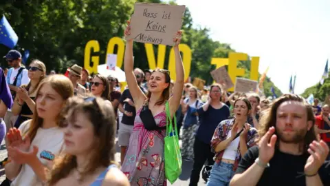 Getty Images A protester holds up a poster reading "Hate is not an opinion" as she takes part in a demonstration to defend democracy against the far-right on June 8, 2024 in Berlin