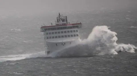 The Manxman, a large boat, on choppy waters with a large wave crashing to the right.