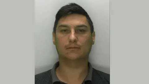 A police mugshot of Clinton Brown, a white man in his 40s with short dark hair