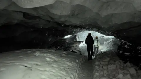 Two people walking in an ice cave