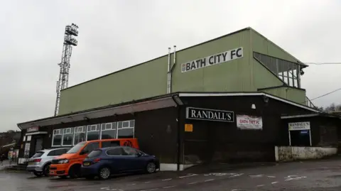 An exterior view of one of the stands at Bath City, with cars parked in front