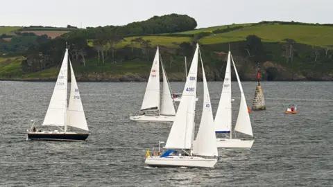 Hugh Hastings Four sailboats with sleek designs and modern sails on the water. All have white sails.
