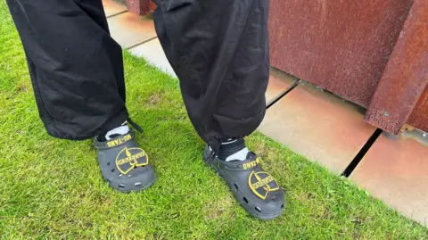 A close up of a pair of crocs decorated with Wu Tang Clan symbols