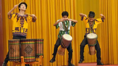 VCG / Getty Images Chinese men beating traditional African drums at the Great Hall of the People in Beijing, China - Wednesday 4 September 2024 