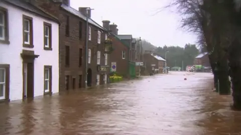A row of houses with brown water coming up to the bottom of their ground floor window sills.