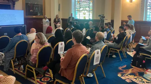 Room full of people watching a presentation on a screen