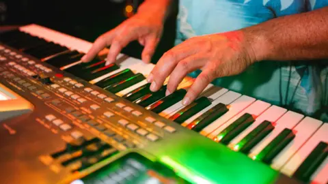 Patricio Nahuelhual/Getty Images A man's hands are playing a keyboard in a music studio