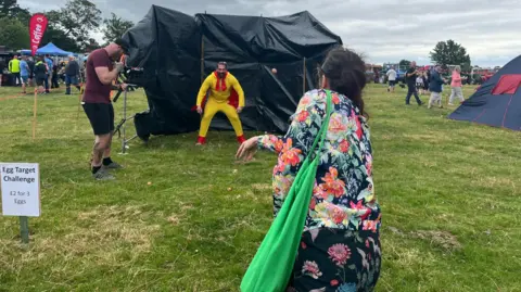 Beth Pritchard/BBC a woman throwing an egg at a human target