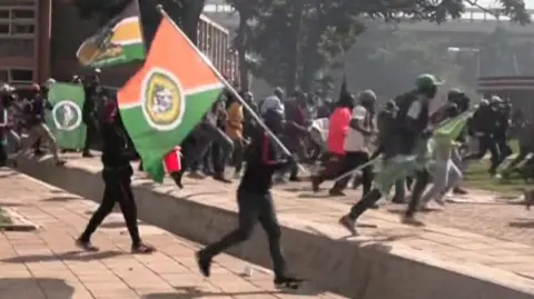 Group of people waving green and orange flags run from left to right