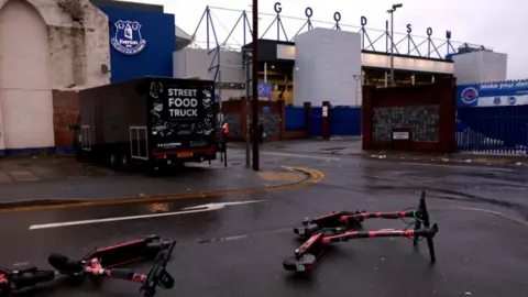 PA Two electric scooters blown over in the wind outside an empty Goodison Park