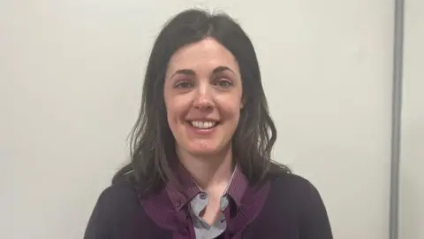 Train driver Elizabeth Kirby with shoulder length brown hair and wearing a purple polo top with a grey collar