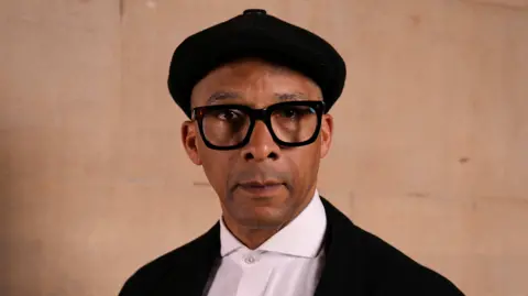 Getty Images Jay Blades wearing a black cap, black jacket and white shirt