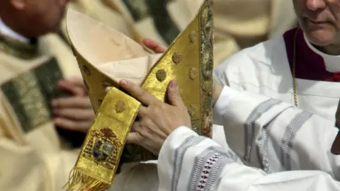 The golden papal hat being placed on someone's head