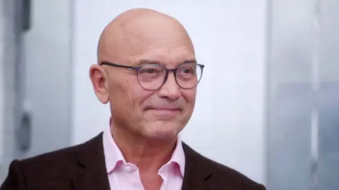 Gregg Wallace in pink shirt and brown/maroon jacket 