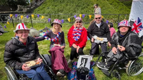 A group of people wearing union jack hats sitting in a field in Cardiff Castle