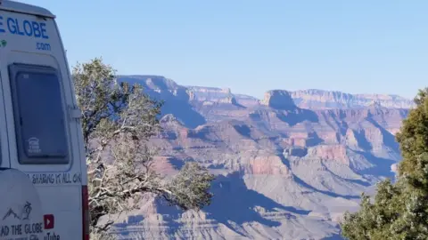 Tread The Globe The back end of a camper van with some trees and part of the Grand Canyon in the background