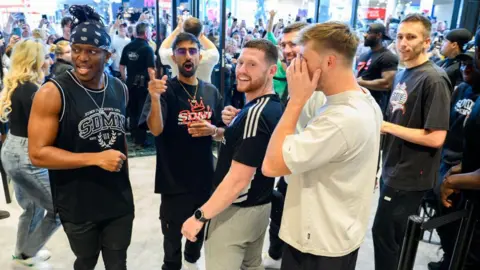 Getty Images KSI, Vikram Singh Barn, Ethan Payne, Harry Lewis, Joshua Bradley, TBJZL and Simon Minter inside a shop - Lots of fans are seen in the background, filming on their phones from outside the store.