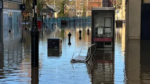Chippenham town centre after flooding from Storm Bert. Bollards along the street can be seen, as well as businesses along either side of the road. They are all closed due to the flood.