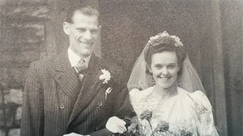 Neil Reynolds A picture of Jim and Nellie Reynolds on their wedding day in 1947. It is black and white.