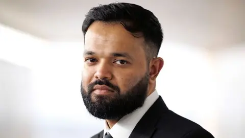 Getty Images Azeem Rafiq, a bearded man wearing a white shirt and black blazer. The background is plain light.