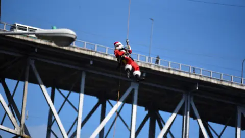 Hector Chacon dressed as Santa Claus abseiling down a bridge in Guatemala City.