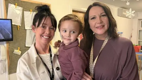 Nursery manager Katie Unsworth and teaching assistant Shelley Marston are holding Chester, who has a feeding tube, for a posed photograph at the nursery. 