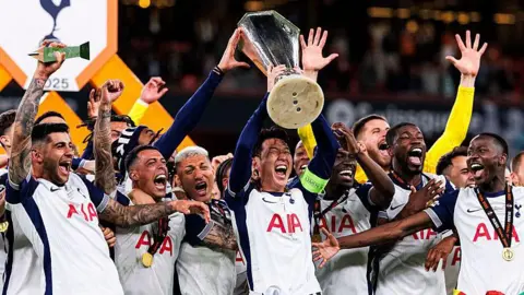 Son Heung-min lifts the Europa League trophy into the air alongside his Tottenham team-mates