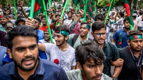 AFP via Getty Images Young protesters wave the Bangladesh flag as they take to the streets of Dhaka in 2024