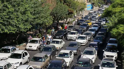 Getty Images Vehicles wait in lines of traffic as people queue to get out of Tehran through road in the west of the city on 15 June 2025