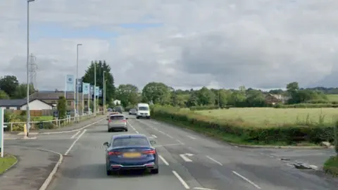 Google A new housing development is seen on one side of a road, with fields and a road on the right. 