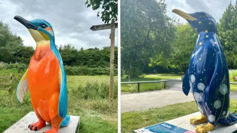 St Richard’s Hospice An orange and light blue penguin sculpture to the left and a darker blue sculpture with stars and flowers to the right