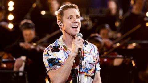 Jake Shears standing on a stage singing into a microphone