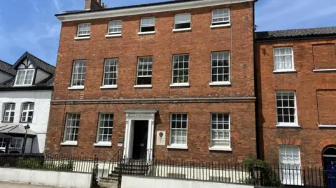 LDRS An 18th Century red brick double-fronted town house with three floors and white-framed dormer windows.